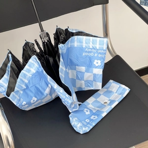 Detail of light blue checkered sun umbrella with daisy pattern and zipper pouch