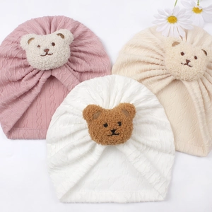 Detail of three soft baby bear beanies in pink, beige and white colors