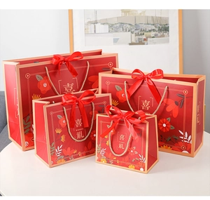 Detailed view of four sizes of red gift bags with silk bows and golden rope handles