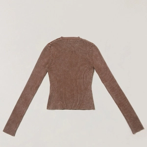 Dettaglio del maglione in maglia marrone lavato con pietre con trama a costine e cuciture slim