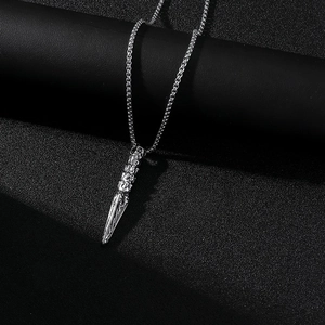 Détail macro du pendentif poignard en acier argenté avec gravure crâne et chaîne maille