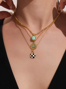 Close-up of triple-layered gold necklace with green turquoise and checkered enamel pendant