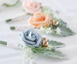 Close-up of Morandi blue artificial rose boutonniere with gold beads and white lace wrap