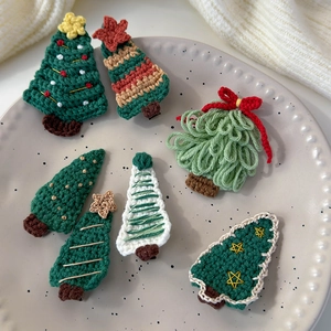 Detail view of handmade crochet Christmas tree hair clips in festive colors and styles