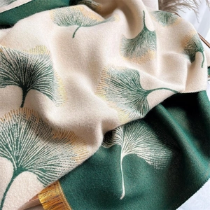 Detailed texture of double-sided cashmere scarf with ginkgo leaf pattern and golden fringe