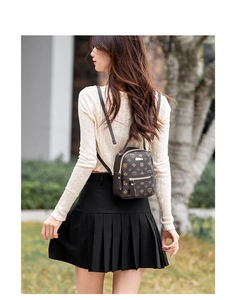 Outdoor model shot of a mini heart print backpack with golden hardware and double zippers