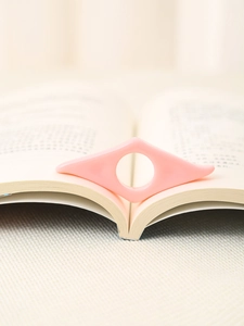 Macro di un supporto per pagine di libri in acrilico rosa per leggere comodamente con una mano
