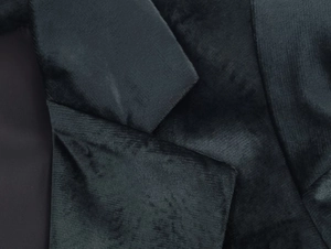 Gros plan du revers d'un blazer en velours noir montrant la texture côtelée et les détails