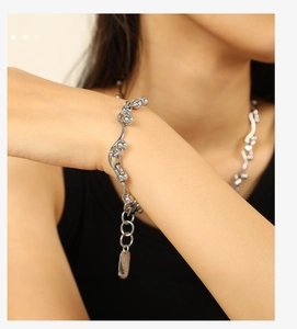 Close-up of silver wavy chain bracelet with metal beads and Lucky engraved charm tag