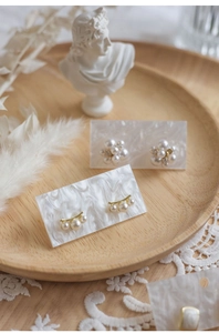 French vintage setup featuring pearl earrings on marble cards in a wooden tray