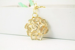 Macro detail of beige rhinestone camellia flower keychain with golden lobster clasp