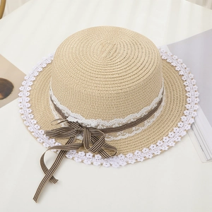 Close-up of woven straw hat with delicate white lace edge and black gingham ribbon bow