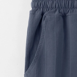 Dettaglio dei pantaloni a righe in lino da uomo con vita elastica e tasche laterali