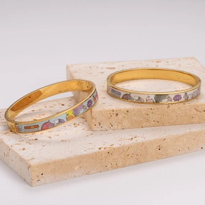 Elegant gold-tone enamel bangle featuring intricate rabbit and floral patterns in cream white