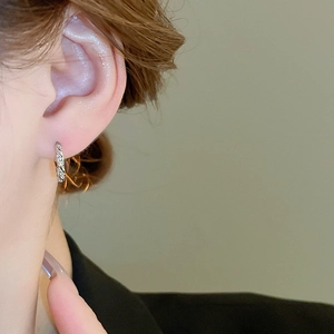 Close-up of minimalist silver hoop earring with cubic zirconia on model ear