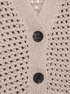Close-up of beige knit cardigan featuring marble-textured buttons and hollow crochet details