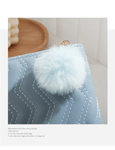 Détail macro du porte-monnaie bleu clair avec coutures ondulées et pompon en peluche
