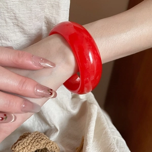 Detailed view of the thick-walled red resin bangle with a polished glass-like finish