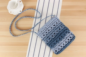 Detail of hand-woven gradient blue shoulder bag showing hollow knit texture and strap