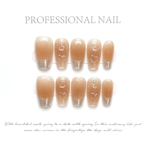 Detail of nude pink press-on nails featuring silver French tips and 3D heart motifs