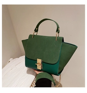Detail of dark green wing bag featuring crocodile texture and suede panel with gold clasp