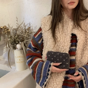Detailed close-up of a dark grey plush polka dot pouch held by a model in a cozy setting