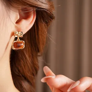 Gold-plated square resin drop earrings in amber brown featuring textured metal design