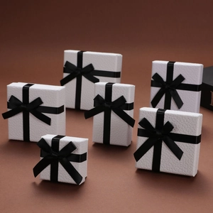 Detail of white jewelry gift boxes with black ribbon bows and litchi texture finish
