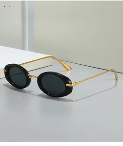 Detail of vintage oval sunglasses with black frame and gold metal temples on grey surface