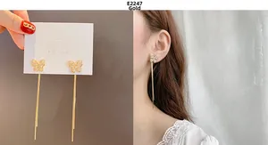 Detail view of long gold butterfly tassel earrings with sparkling zircon on model and card