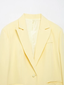 Detailed close-up of pale yellow blazer lapel and smooth professional fabric texture