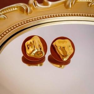 Detail of red-brown velvet and molten gold resin earrings reflected on a mirror