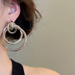 Détail des boucles d'oreilles créoles triple couche argentées portées par le mannequin