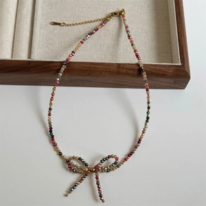 Detail of beaded necklace with faceted crystals, bow charm, and golden lobster clasp