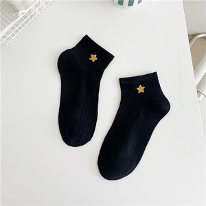 Close-up of black cotton ankle socks featuring delicate gold star embroidery detailing