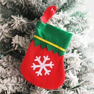 Detail of a red and green felt Christmas stocking with a white snowflake and gold trim