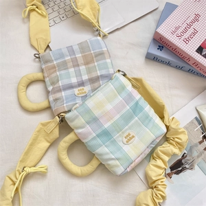 Detail of plaid fabric water bottle bags with yellow shoulder straps on a cozy desk
