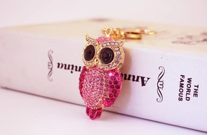 Macro detail of golden owl keychain featuring sparkling pink rhinestones and black gem eyes