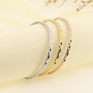 Dettaglio macro di bracciali impilabili in acciaio al titanio con motivi geometrici diamantati