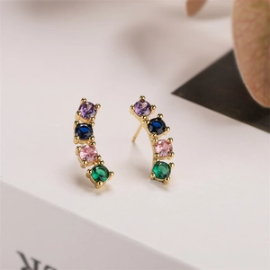 Detailed macro view of gold plated heart cross earrings with colorful gemstones