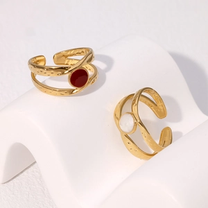 Detail of gold double-layer wave rings with red and white enamel on a white stand