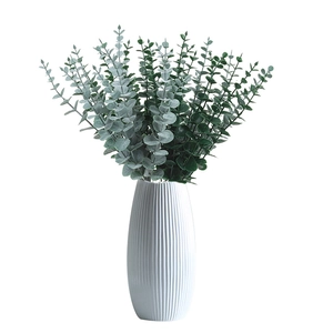 Artificial eucalyptus leaves in a white ribbed vase for modern home floral decoration