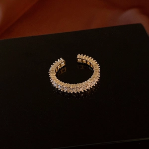 Macro shot of gold-plated ring with clear baguette zirconia on a black mirror