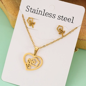 Close-up of golden stainless steel jewelry set with heart and flower pendants on a card