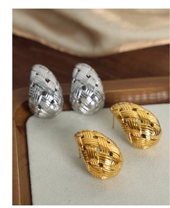 Detailed view of teardrop woven earrings in gold and silver finishes on a wood tray