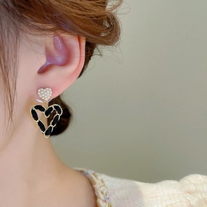 Close-up of heart earrings with pearls and black velvet woven chain detail