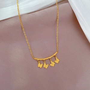 Macro detail of gold butterfly charms and curved bar on a titanium steel necklace