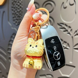 Cute resin cat keychain with gold bell and safe charm on a car key, wood carving style