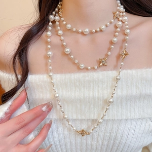 Detail showing elegant layered pearls and gold diamond-encrusted cross charms on the neck