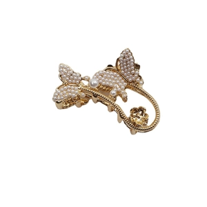 Eleganter Schmetterling Haarklammer aus Gold mit Perlen und Strass auf weißem Hintergrund